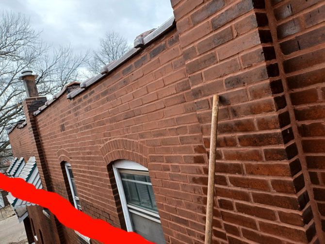 Brick building exterior with red bricks, arched window, and a chimney against a cloudy sky.