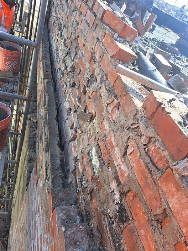 Close-up of a brick wall with mortar, possibly under construction.  A grey vertical structure runs along the wall.