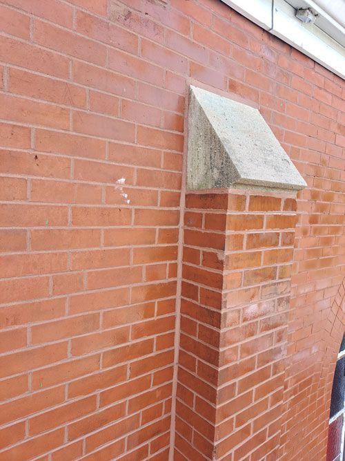 Red brick building corner with a light gray stone cap.
