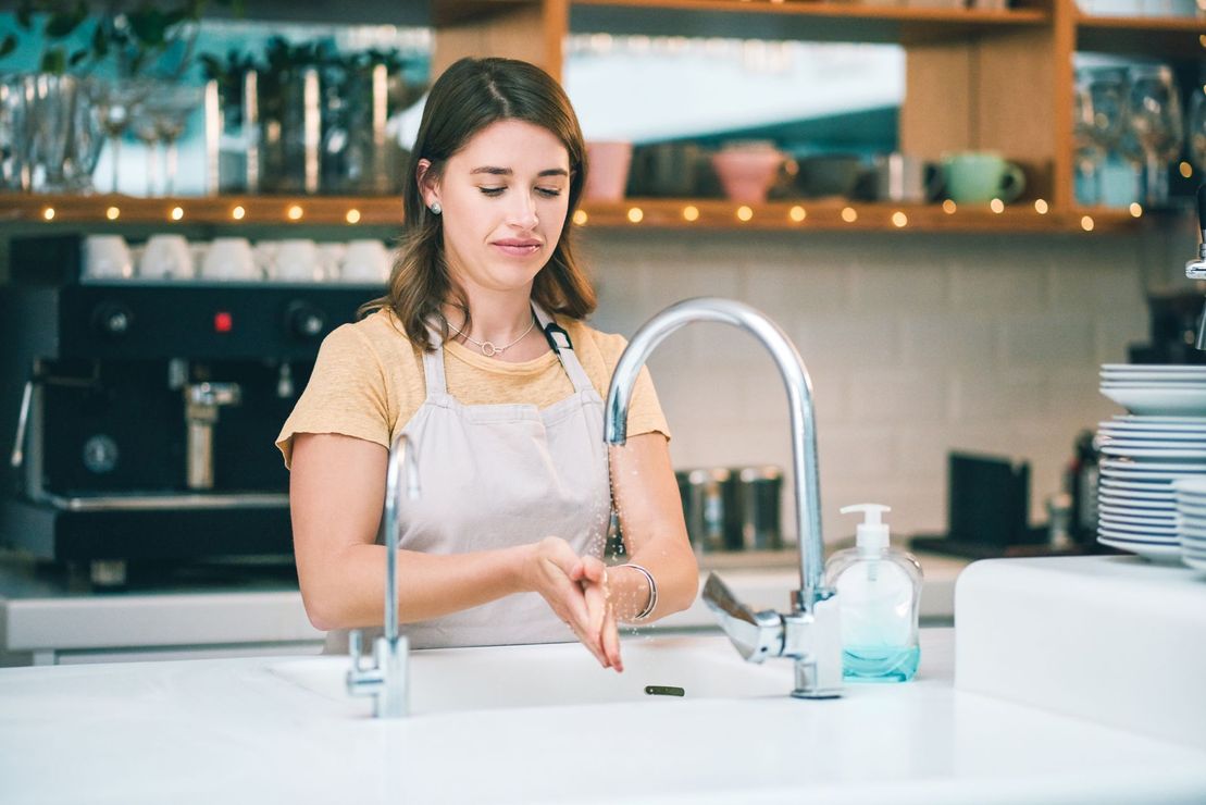 Una donna si lava le mani nel lavandino della cucina.