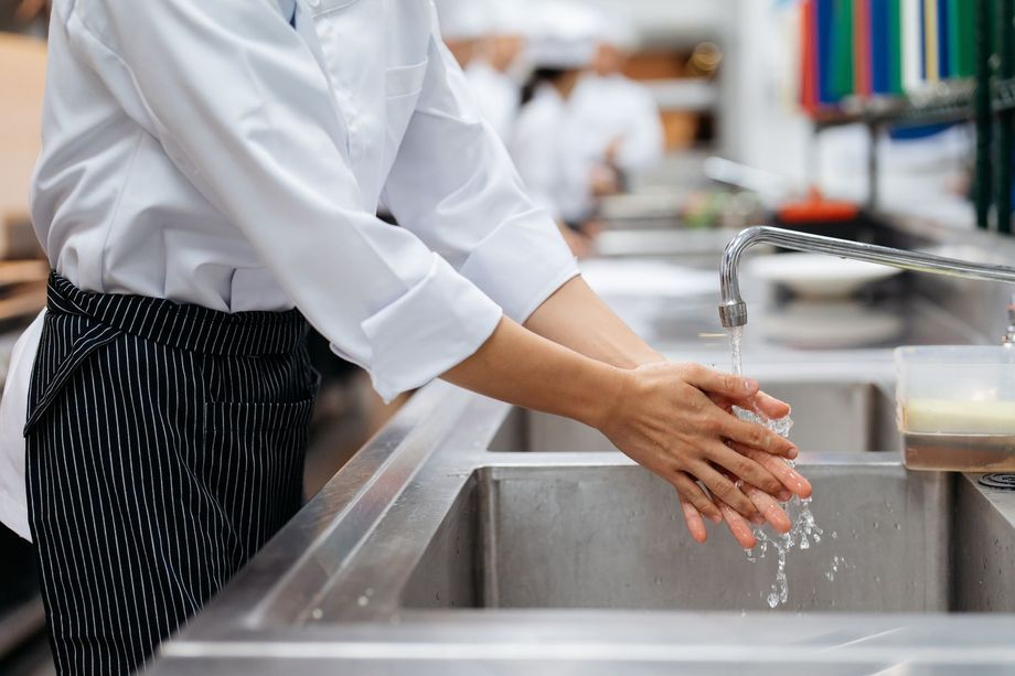 Uno chef si lava le mani nel lavandino della cucina.
