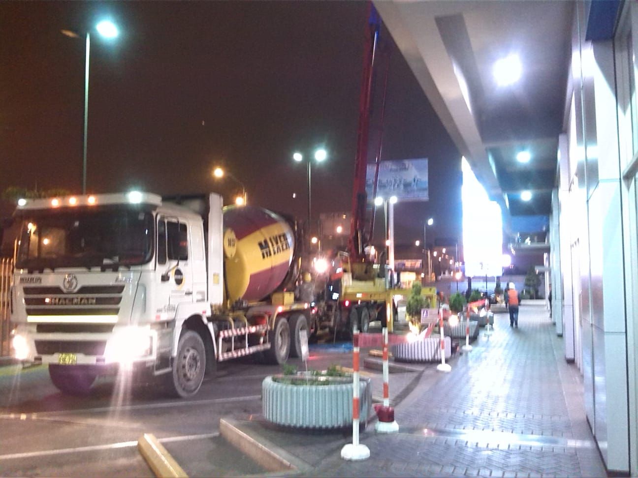Un camión hormigonera está estacionado en un estacionamiento por la noche.