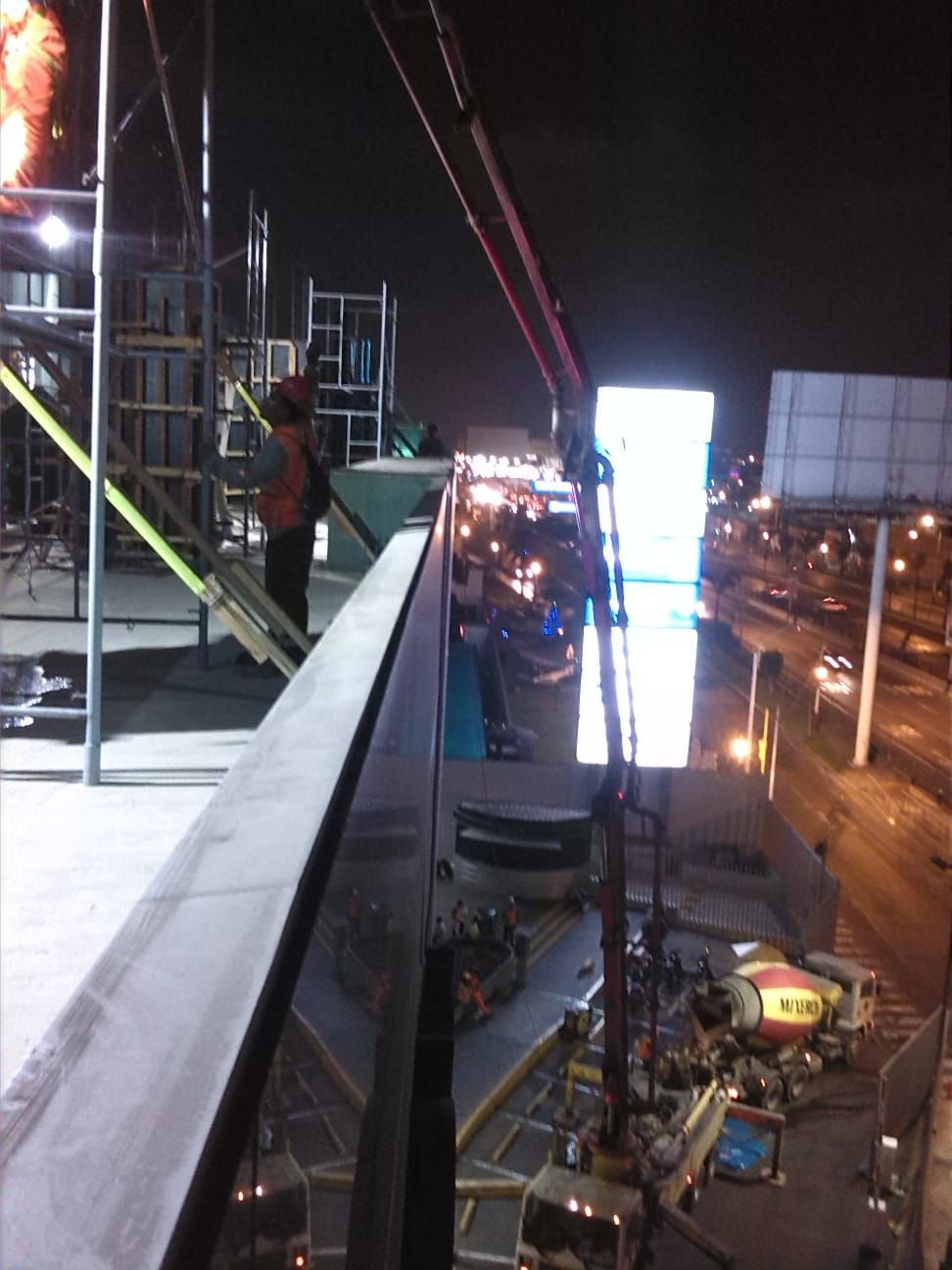 Un hombre se encuentra en un balcón con vistas a una ciudad por la noche.