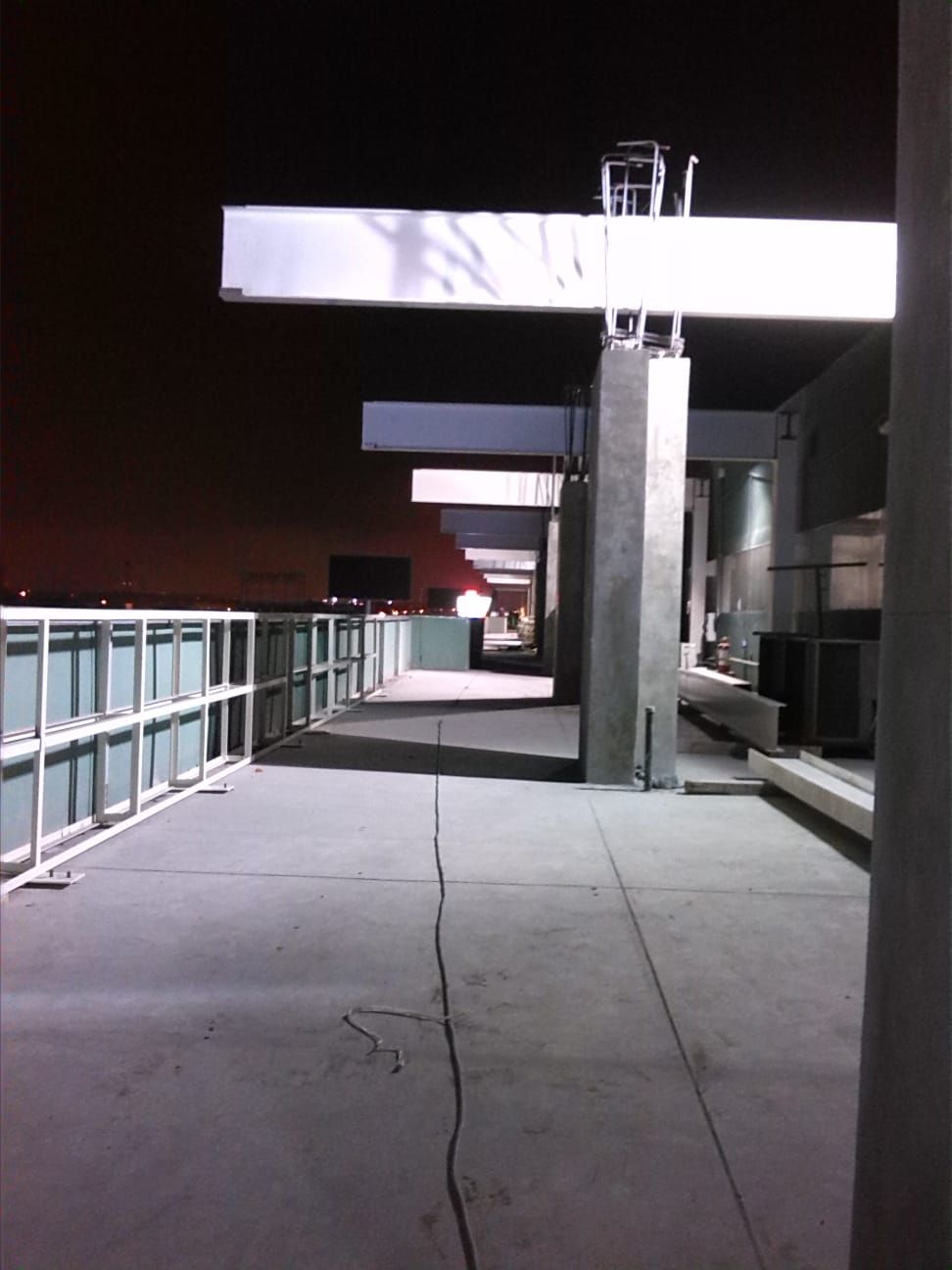 Una pasarela de hormigón con barandilla de metal por la noche.