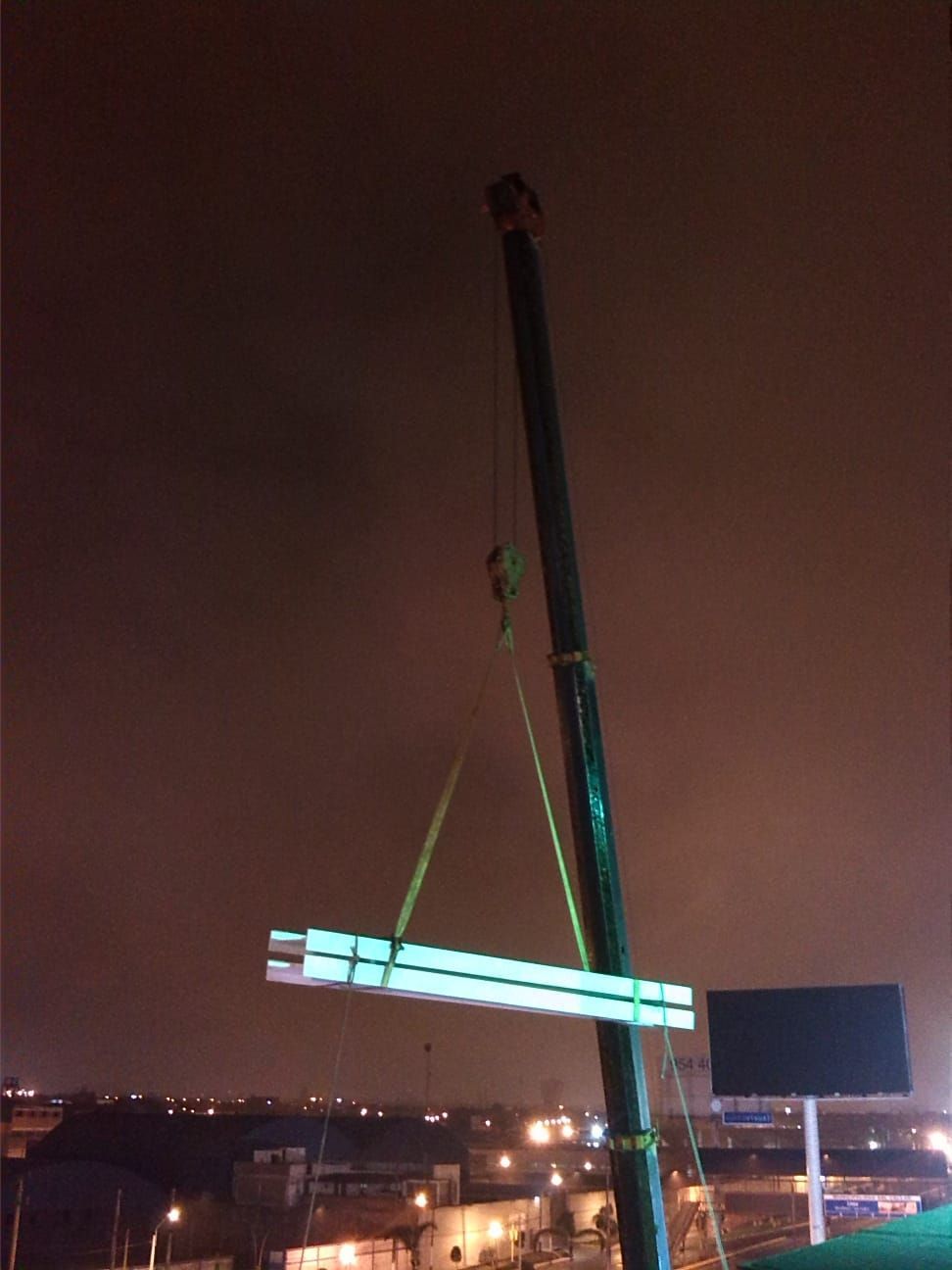 Una grúa está levantando una gran pieza de metal por la noche.