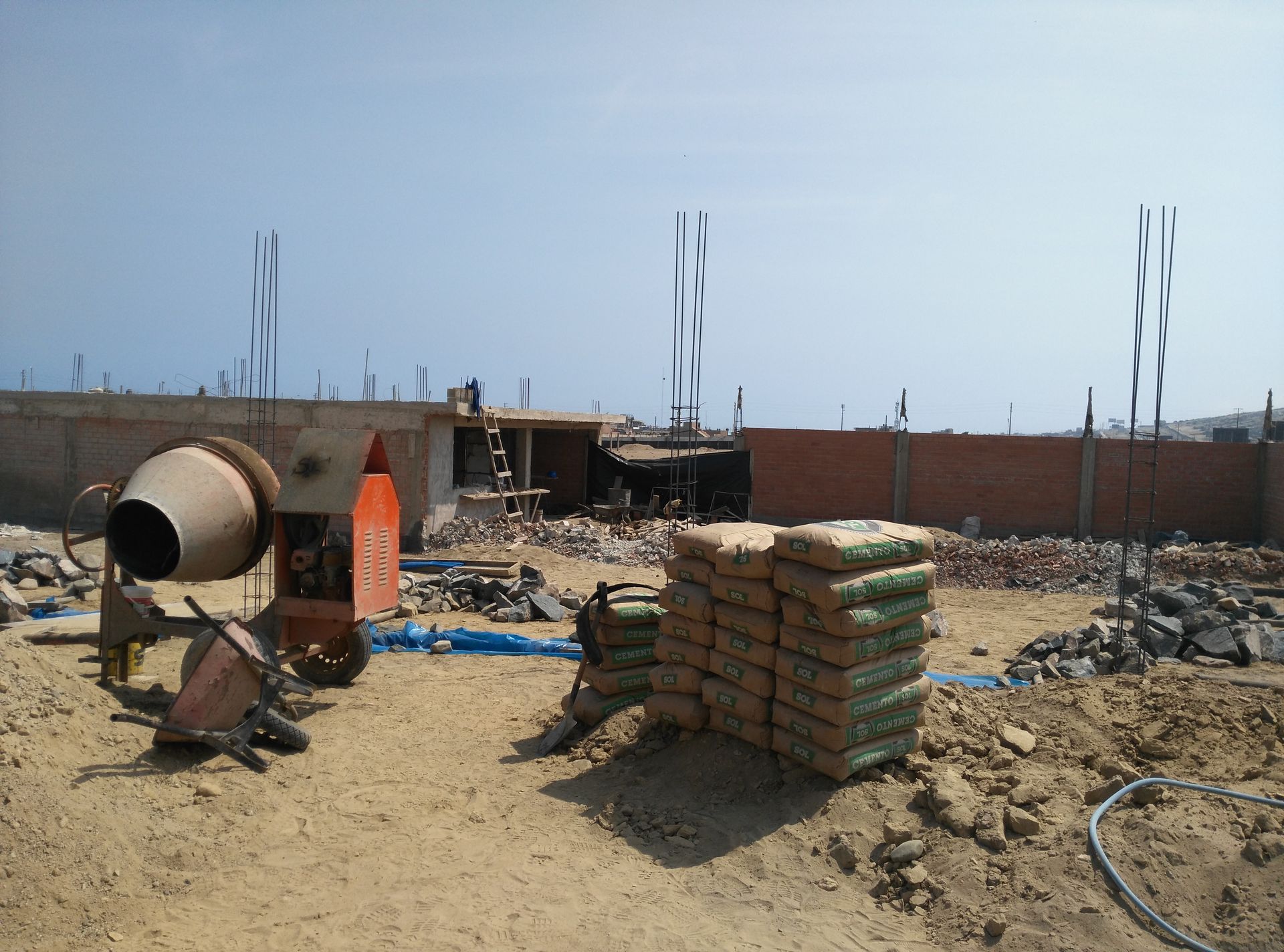 Una obra en construcción con una hormigonera y bolsas de cemento.