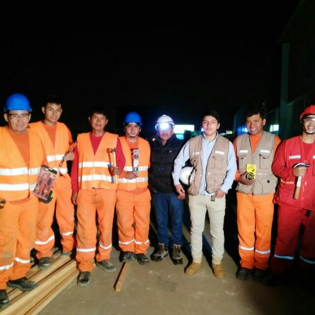 Un grupo de trabajadores de la construcción posando para una fotografía por la noche.