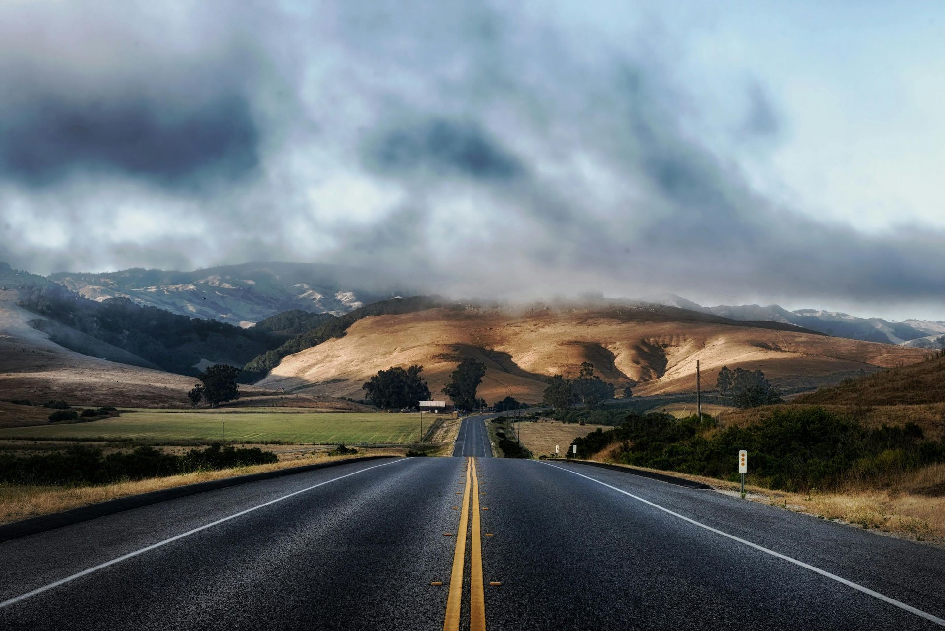 Una carretera con montañas al fondo y un cielo nublado.