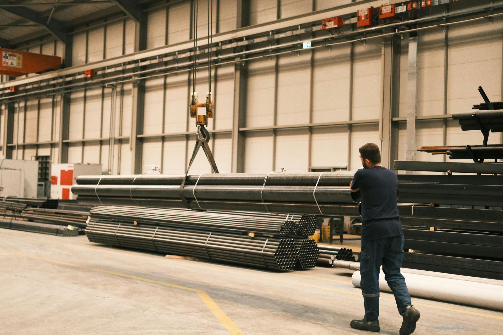 Un hombre está parado en un almacén mirando un montón de tuberías.