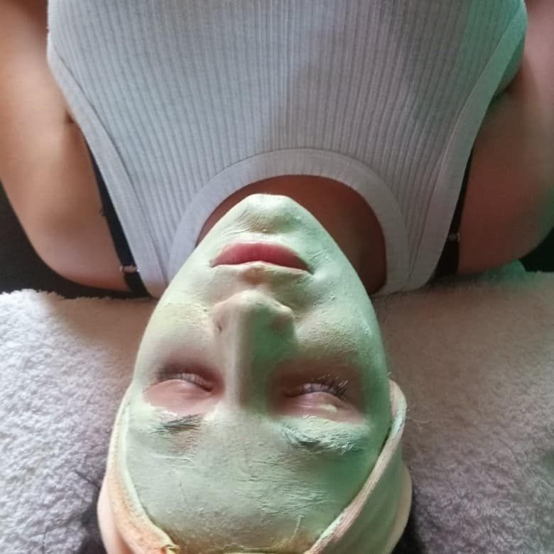 Una mujer está acostada con una máscara verde en su cara.