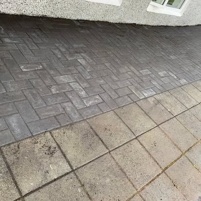 Múrsteinslagað innkeyrsla við hliðina á steyptri hellulögn, upp við vegg húss.