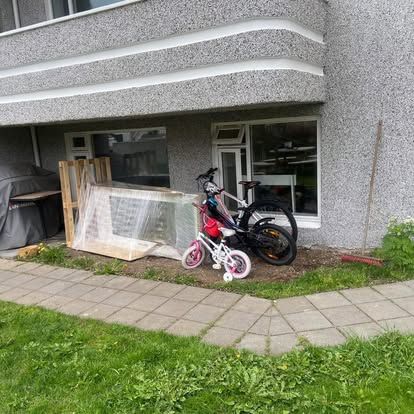 Að utanverðu byggingarinnar með stórum pakka, tveimur hjólum og grasi.