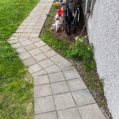 Steinstígur liggur fram hjá grænu grasi og liggur að hjólum sem lagðar voru og byggingu með áferðarvegg.