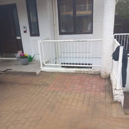 Að utanverðu hvítrar byggingar með múrsteinsverönd, handrið og hurð.