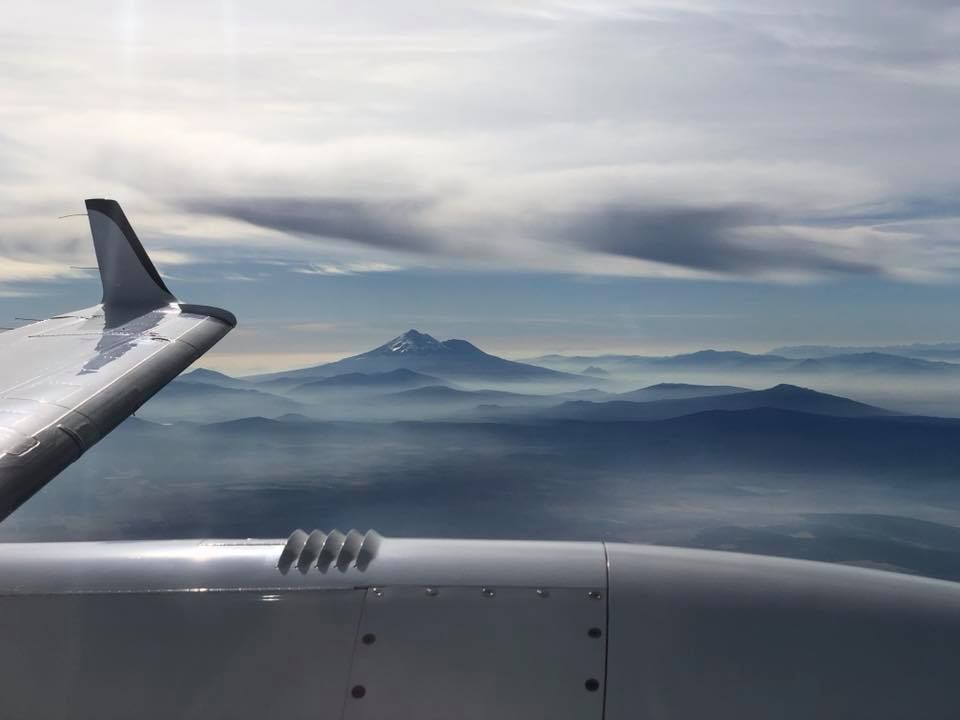 The wing of an airplane flying over a mountain range