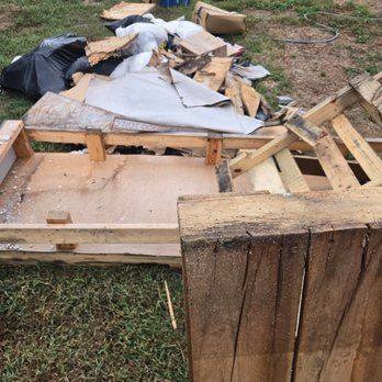 Deconstructed wooden pallets and debris scattered on grass, likely for recycling.