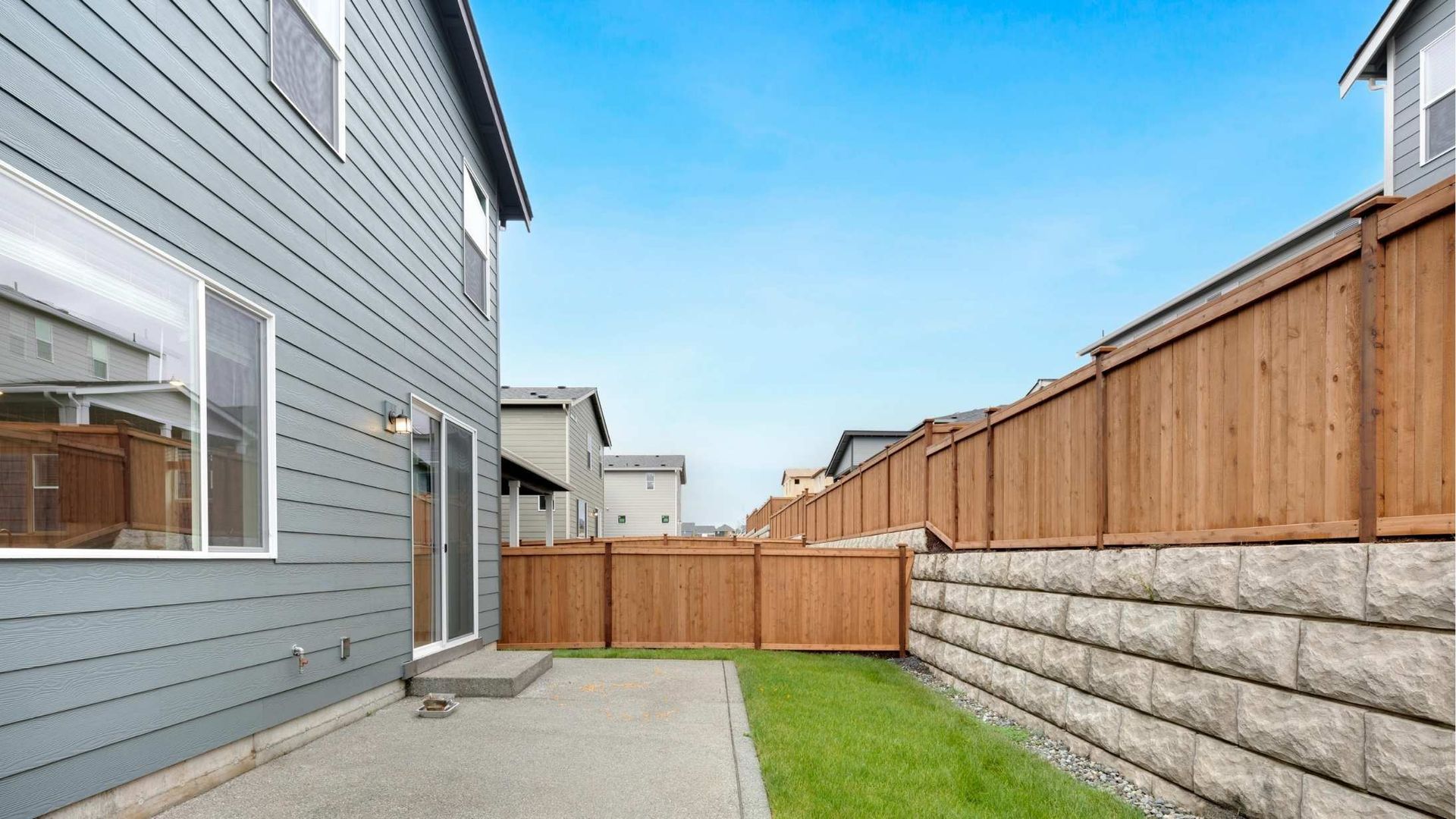 The backyard of a house with a wooden fence and a stone wall.