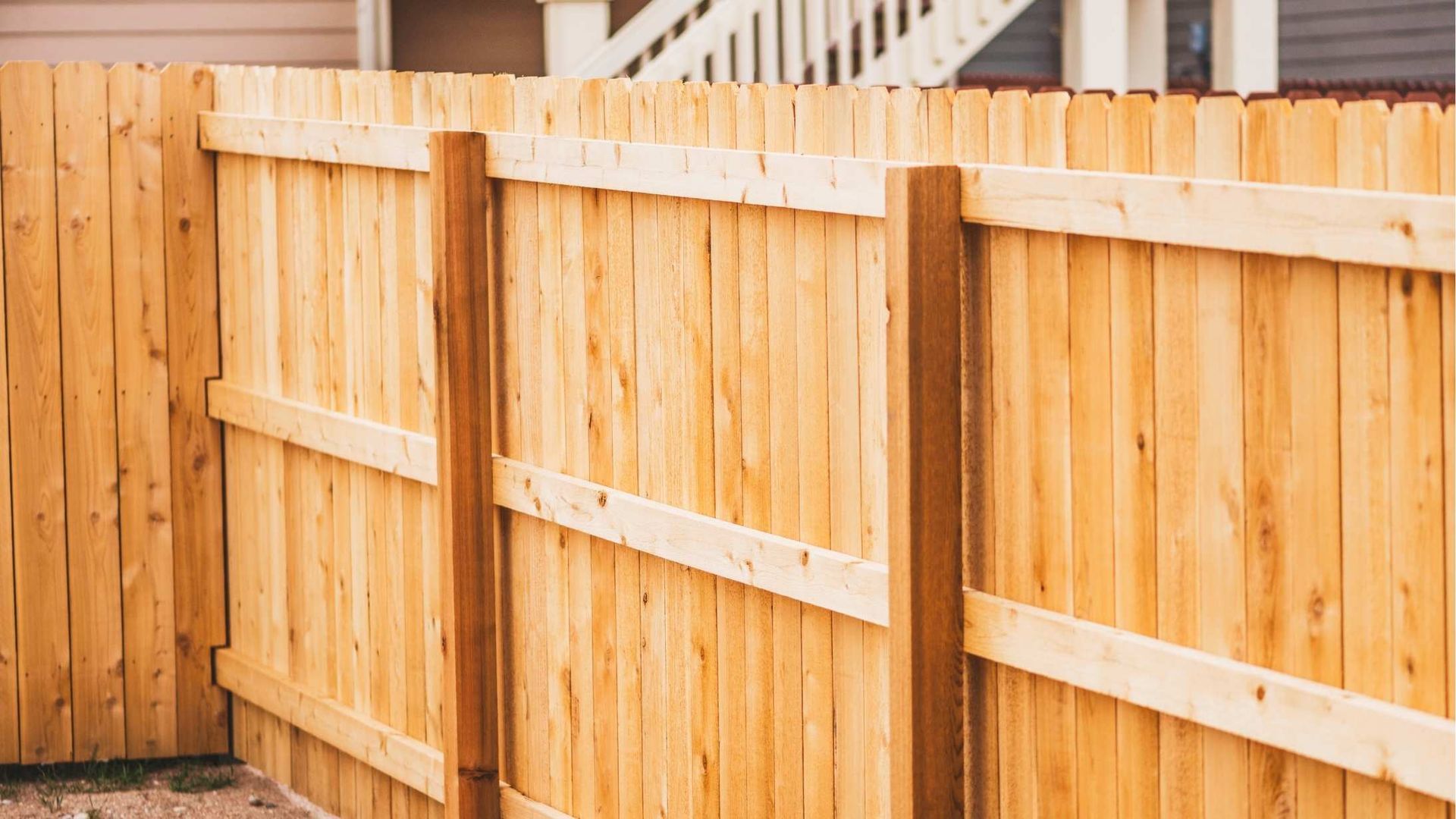 A wooden fence is sitting in front of a house.