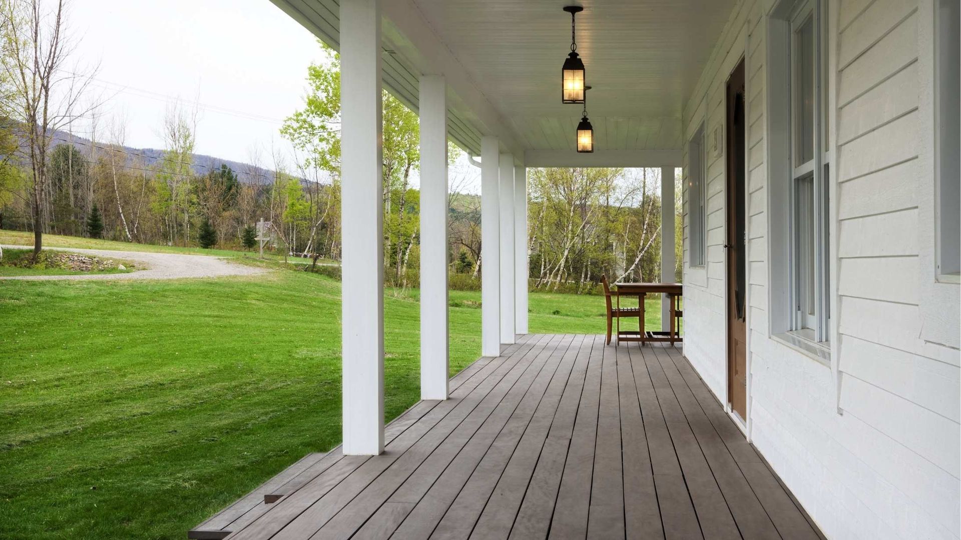 A porch with a wooden floor and lanterns hanging from the ceiling.