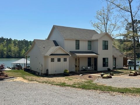 A large white house is sitting next to a body of water.