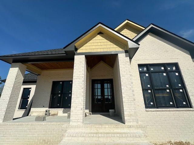 A white brick house with black windows and a blue sky in the background