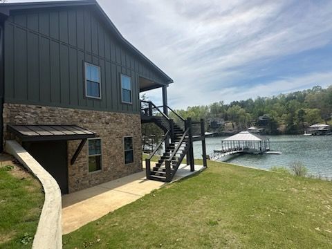 A large house with stairs leading up to a dock next to a lake.