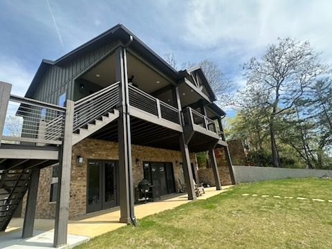 A large house with a lot of windows and balconies is sitting on top of a lush green field.