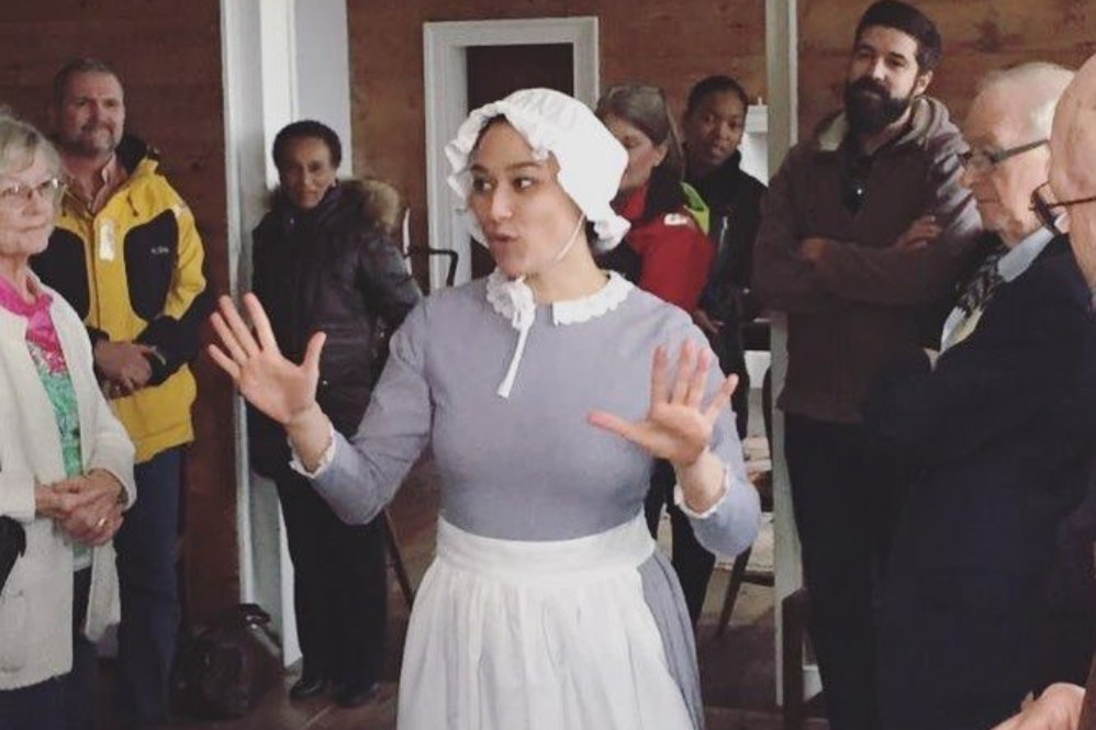 Tea setting on a table, with cups, teapot, and napkins. A window and chairs are in the background.