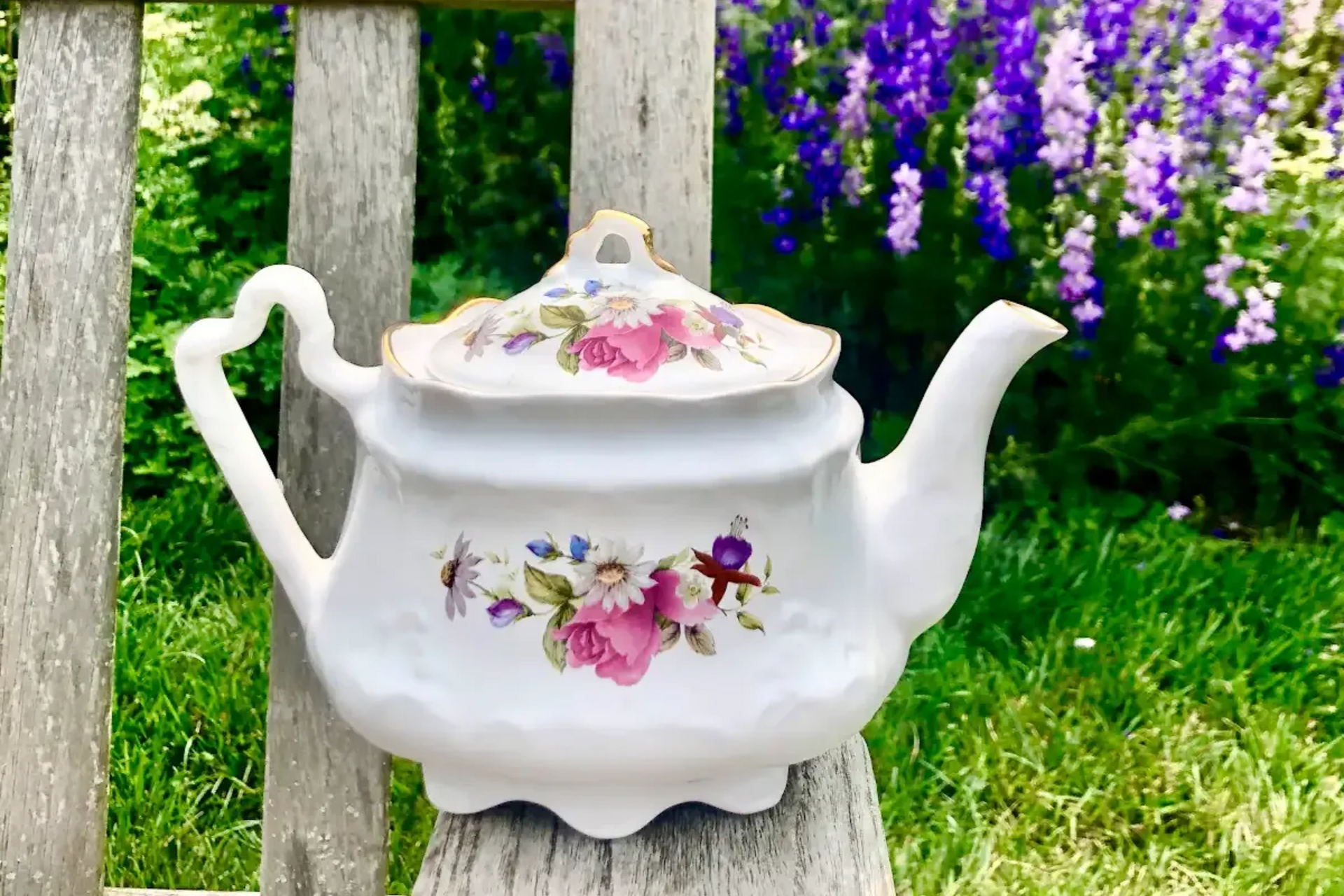 Tea setting on a table, with cups, teapot, and napkins. A window and chairs are in the background.