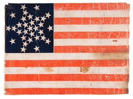 Worn American flag with 38 stars in a circle, red and white stripes.