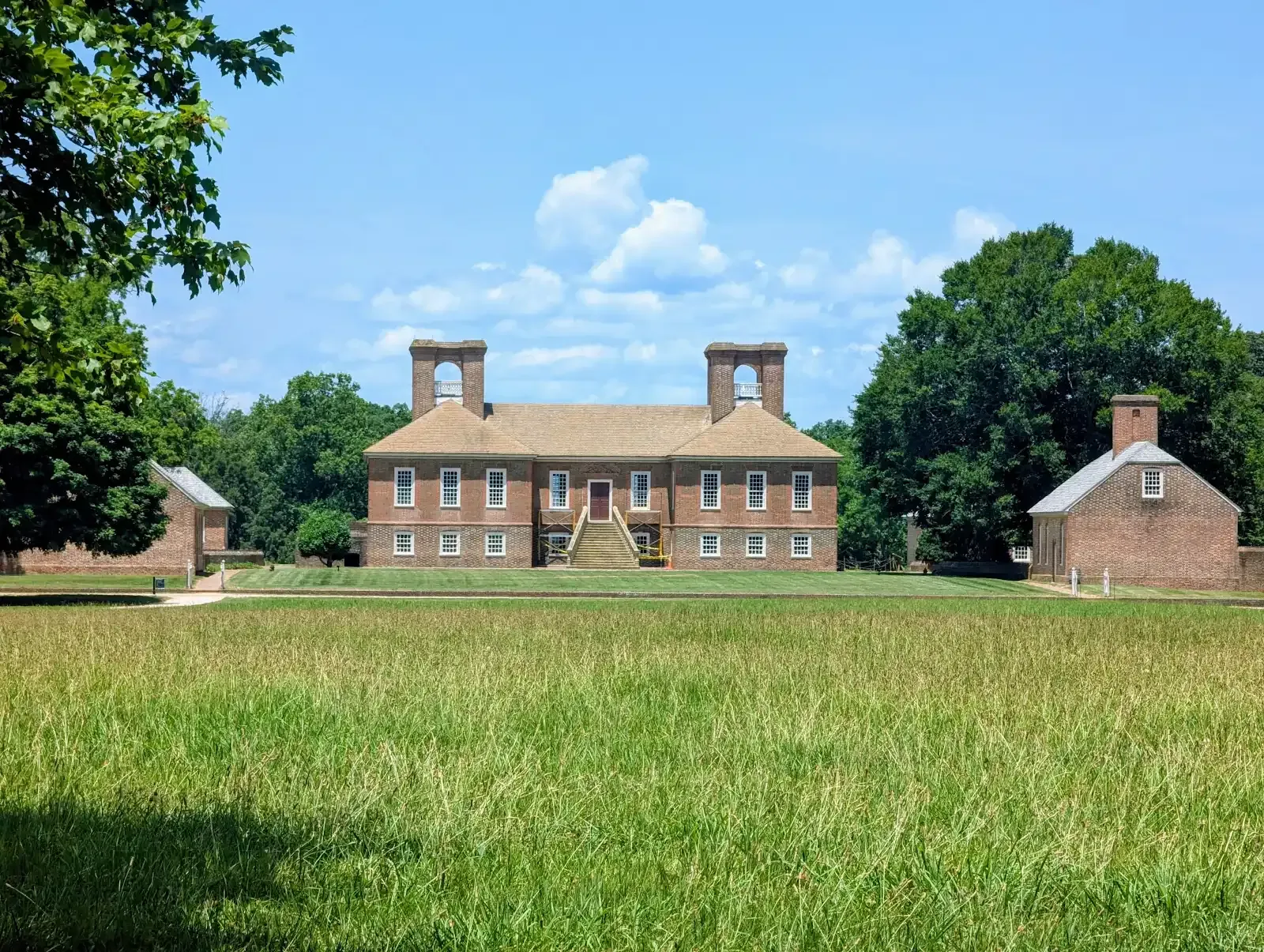 Tea setting on a table, with cups, teapot, and napkins. A window and chairs are in the background.