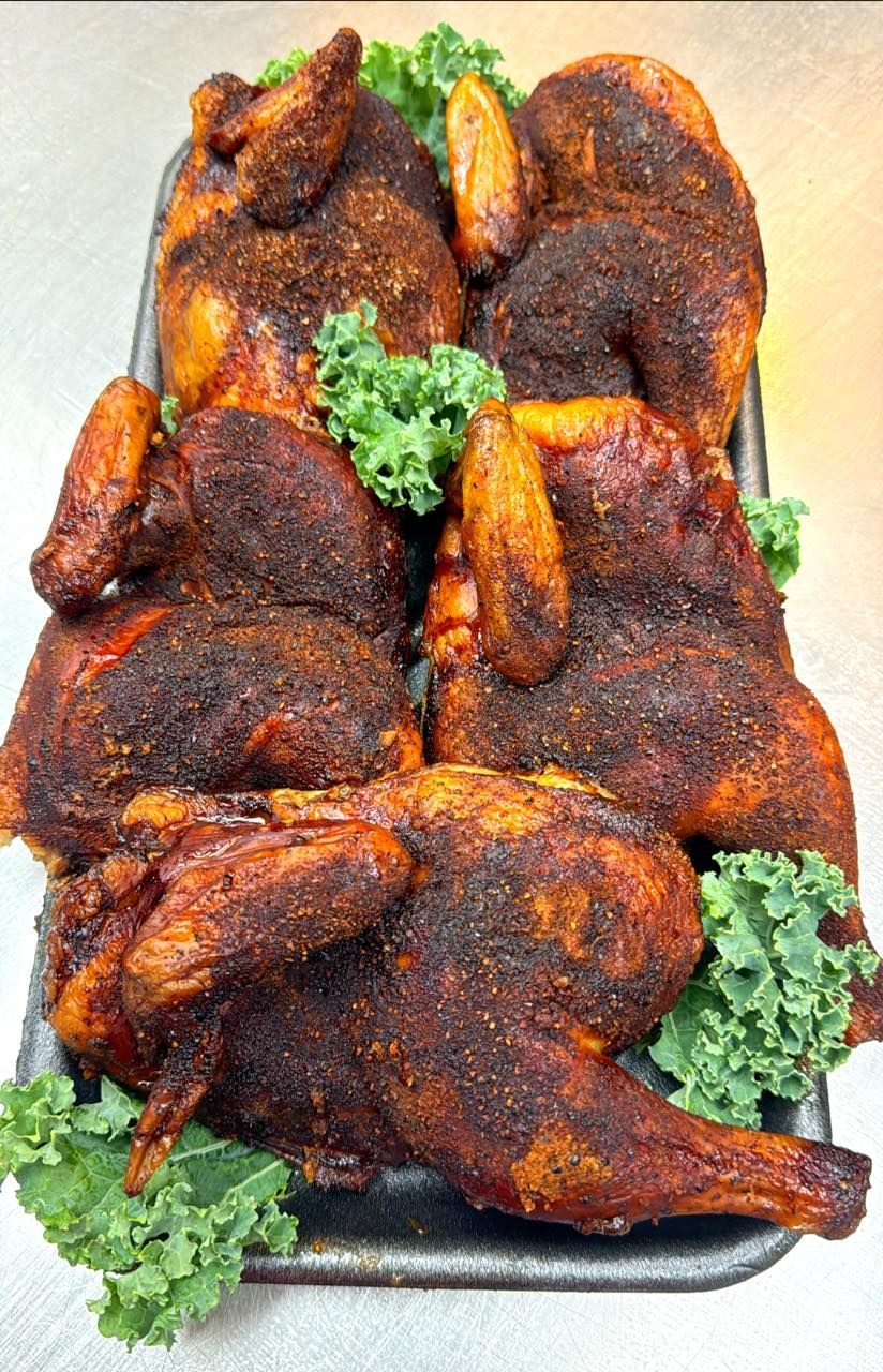 Tray of roasted chickens with a dark, spiced crust and garnished with kale.