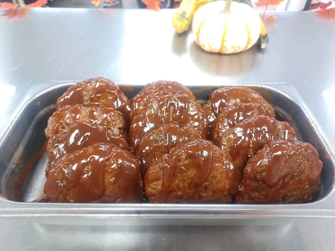 Meatballs in a metal pan, covered in brown sauce.