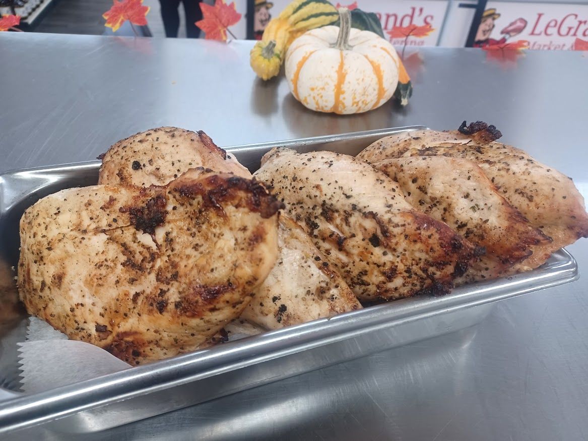 Cooked chicken breasts in a metal pan, with a small pumpkin and gourds in the background.