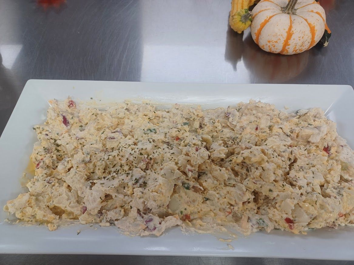 Potato salad on a white rectangular platter, pumpkin and gourds in the background.