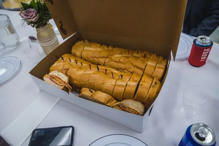 Two large, sliced sandwiches in a box on a table set for a meal.