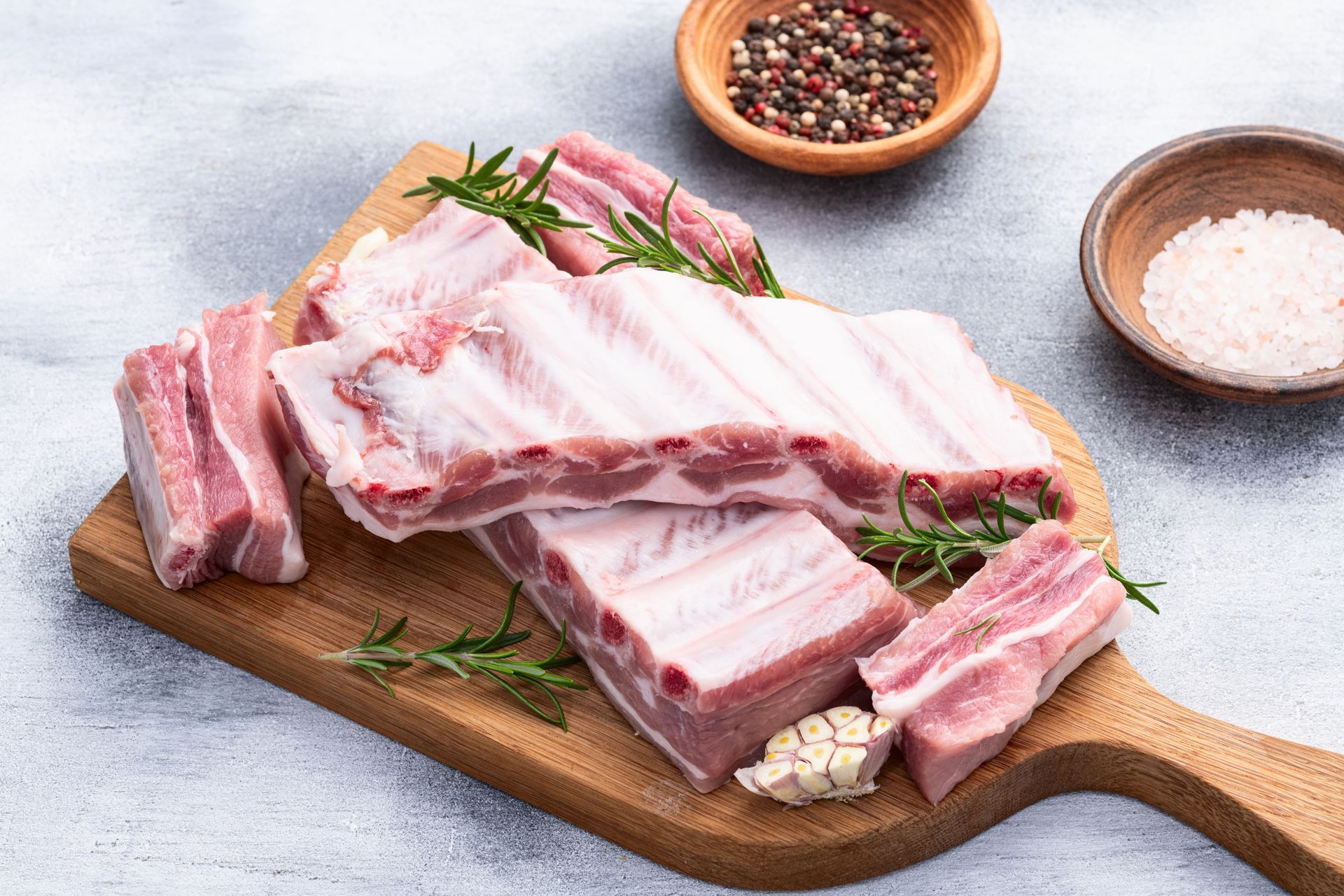 Raw pork ribs on wooden cutting board with seasonings.