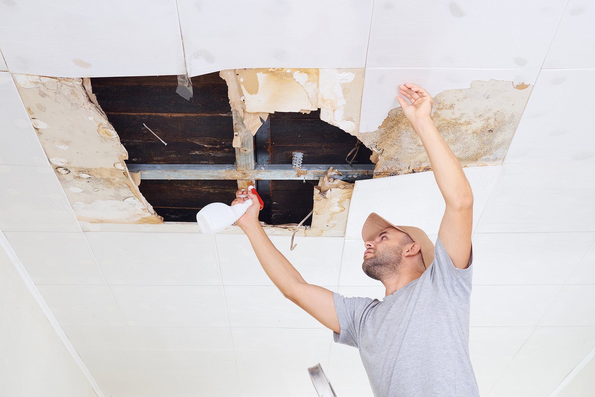 man repairing leaks on ceiling