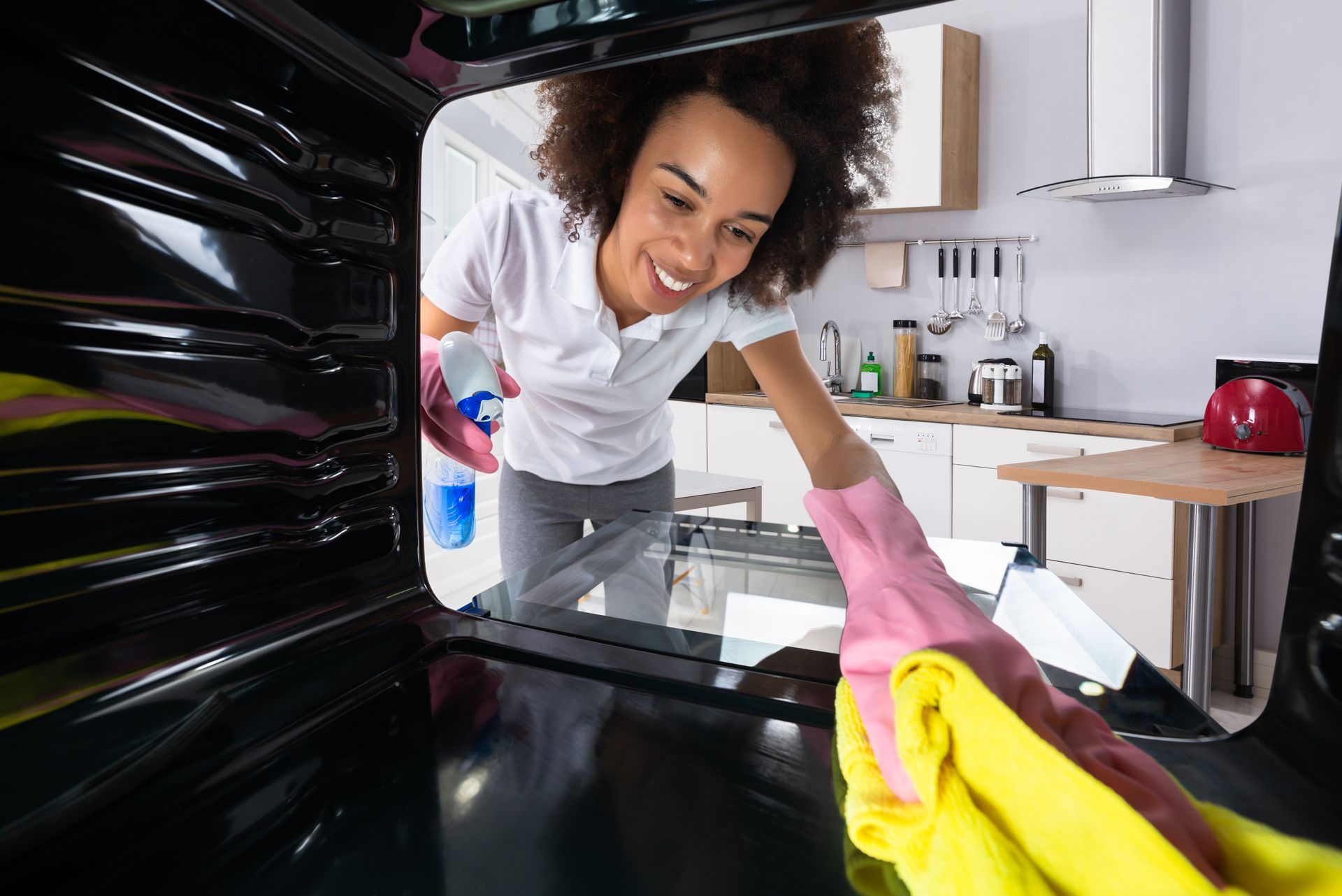 a woman cleaning the oven with microfiber cloth