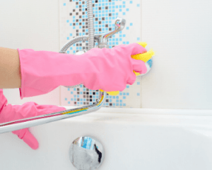 a cleaner wiping a bathroom wall