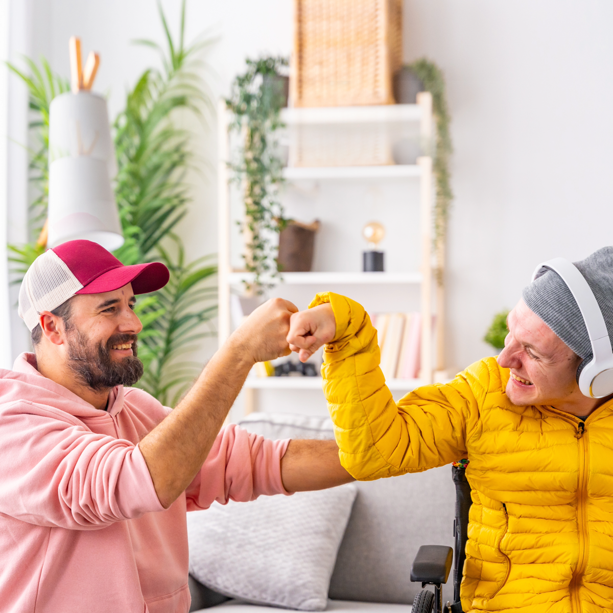 A man and a woman in a wheelchair are giving each other a fist bump.