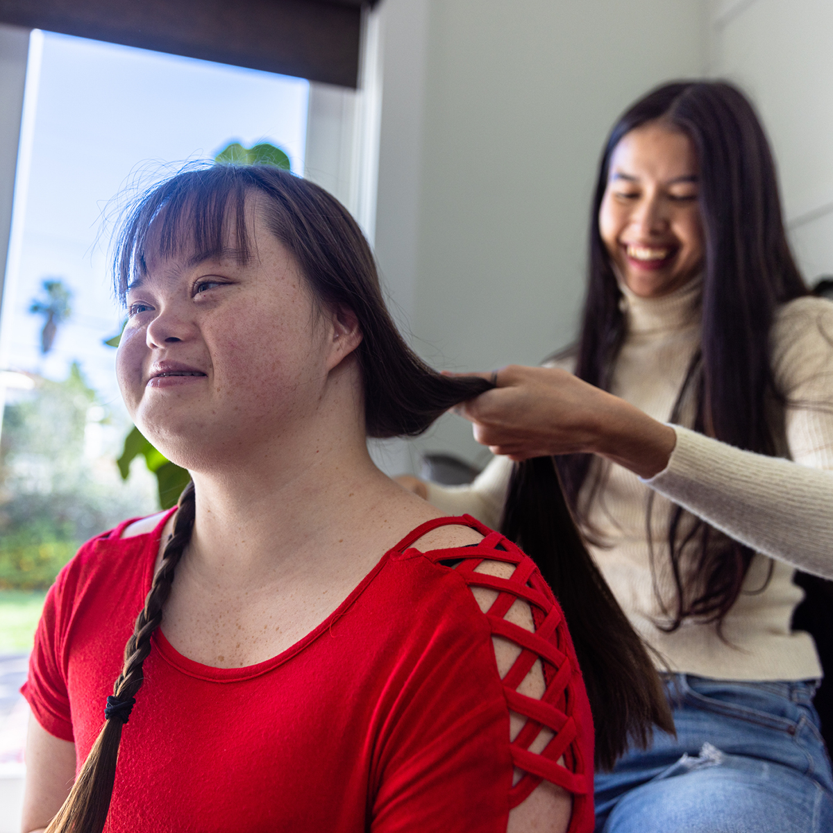 A woman is brushing another woman's hair.