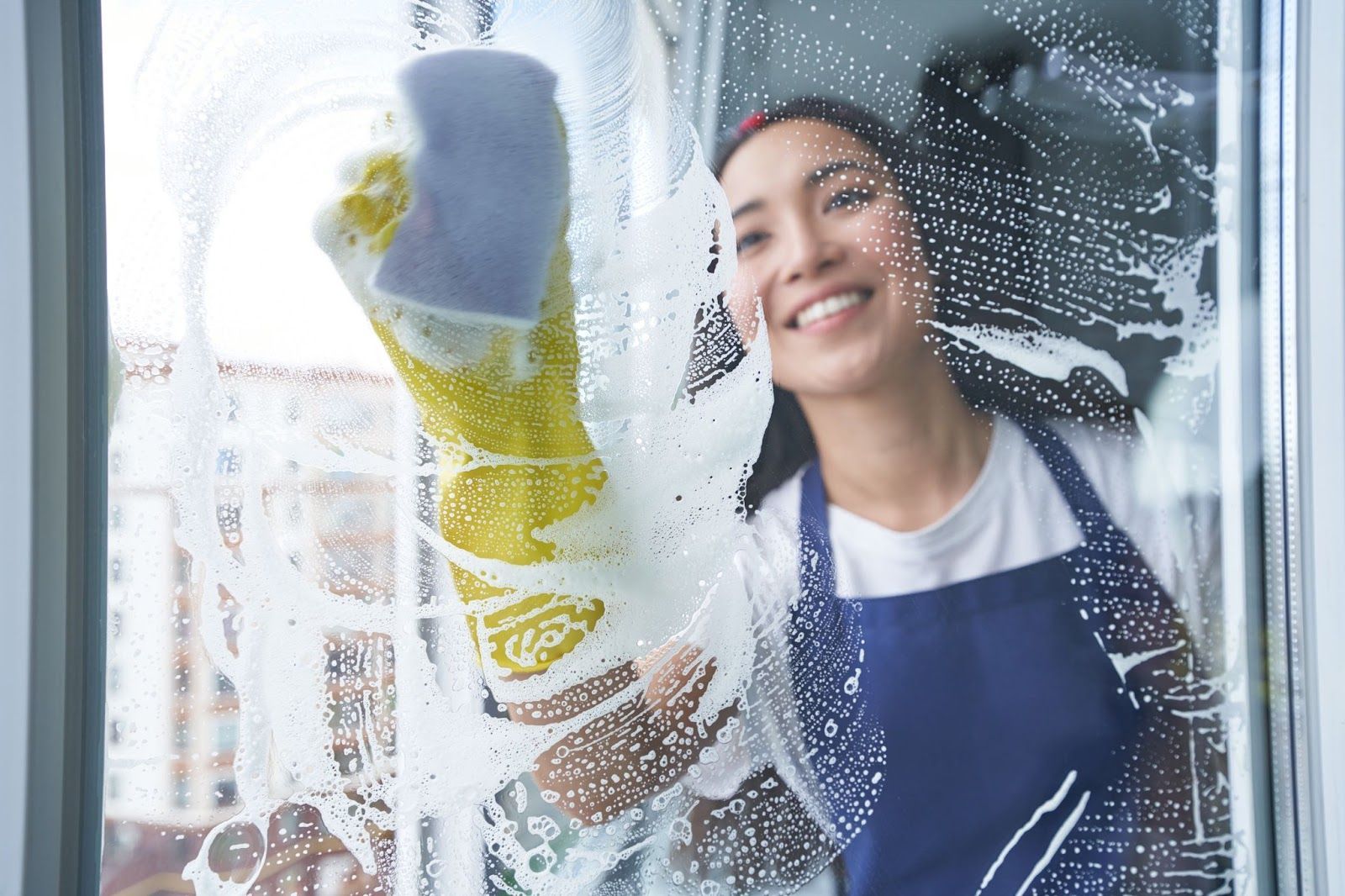beautiful female cleaner washing windows