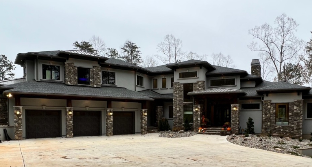 Luxury gray house with stone accents, three-car garage, and circular driveway.