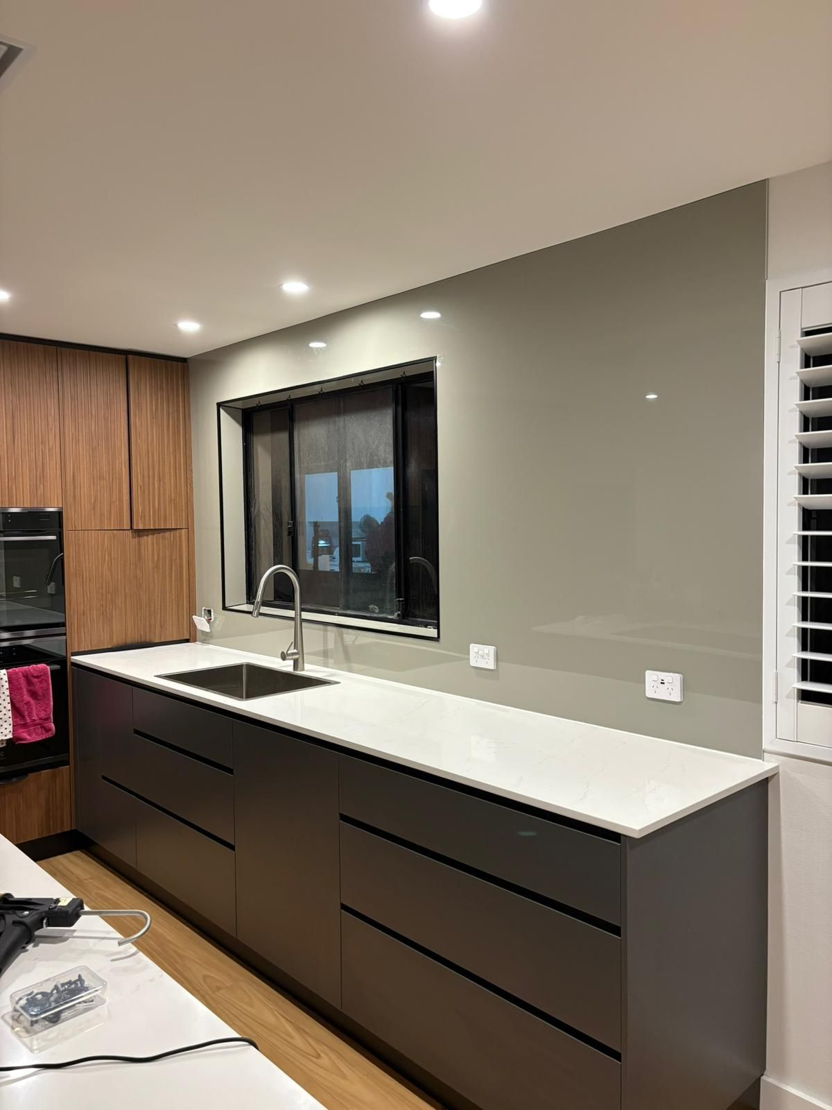 Tools arranged on a white surface: drill bits, tape measure, protractor, screws, wood pieces.