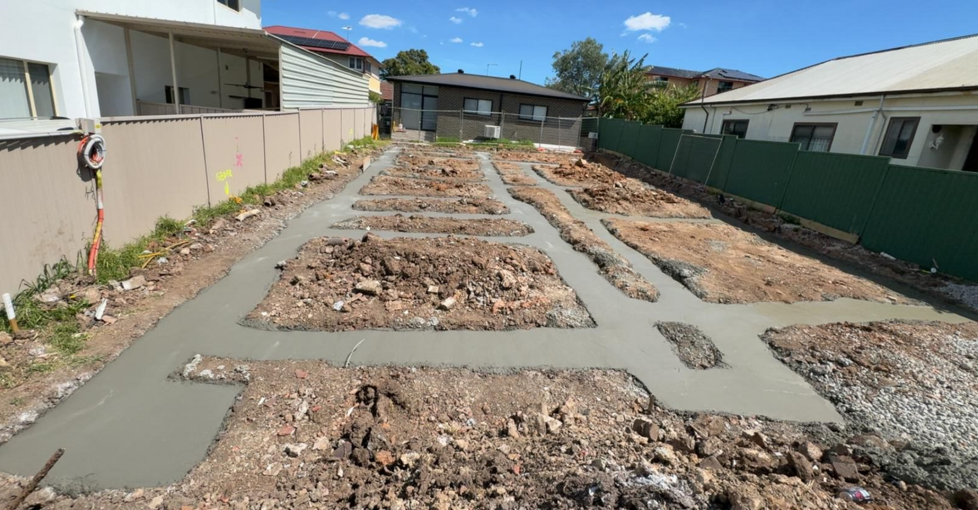 Concrete foundation forms laid out on a dirt lot, ready for building construction.