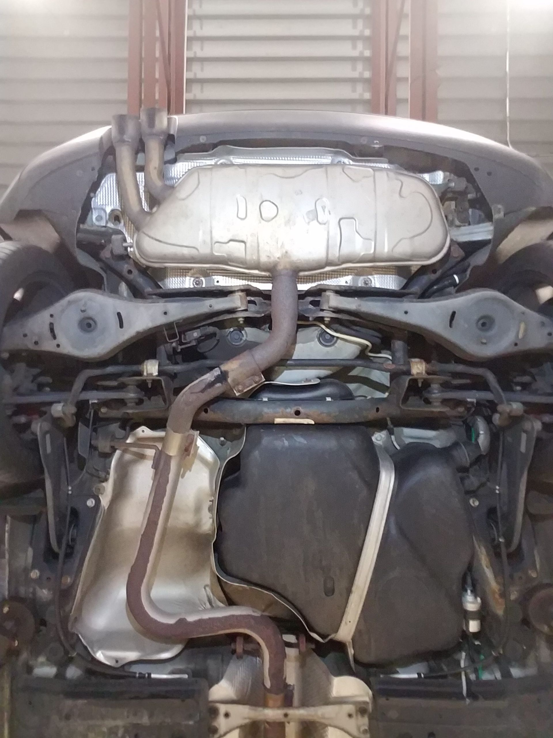 Underside of a car showing exhaust system, fuel tank, suspension, and chassis components. | Autobahn Performance Inc