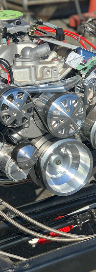 Polished metal engine components: pulleys, belts, and a water pump. | Autobahn Performance Inc