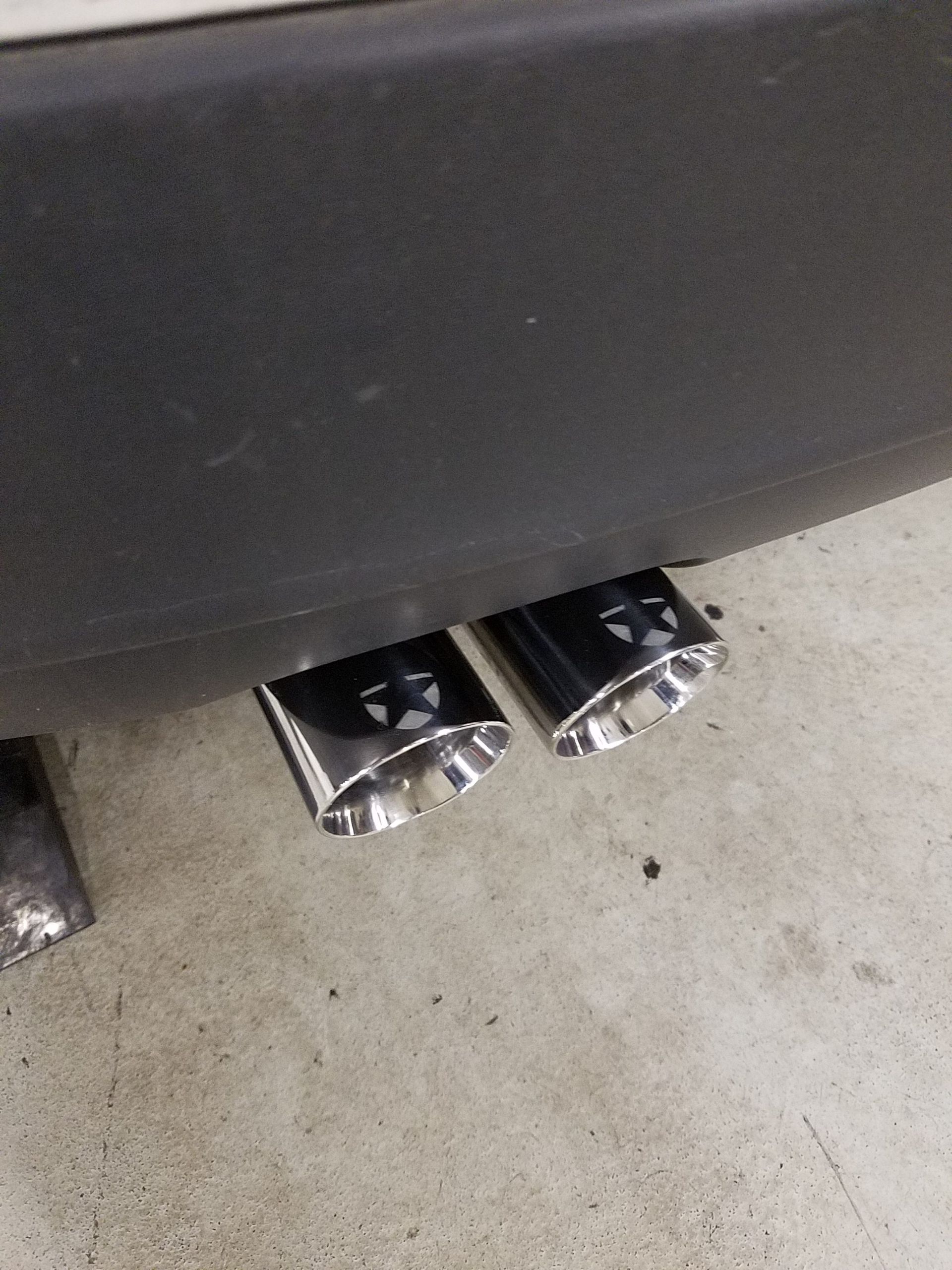 Chrome exhaust pipes on a car's black bumper. | Autobahn Performance Inc