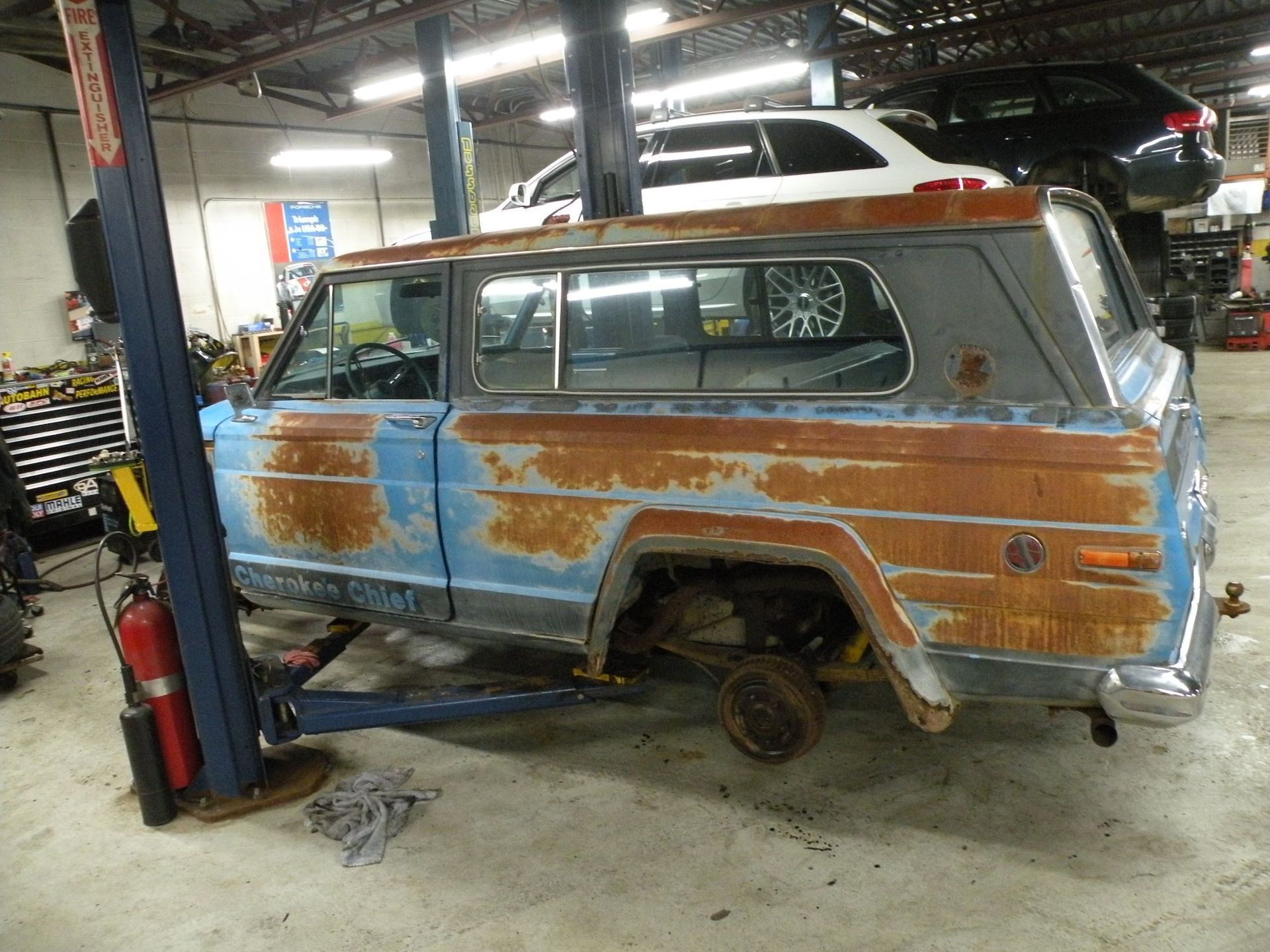 Rusty blue and brown Jeep Wagoneer on a car lift in a garage. | Autobahn Performance Inc